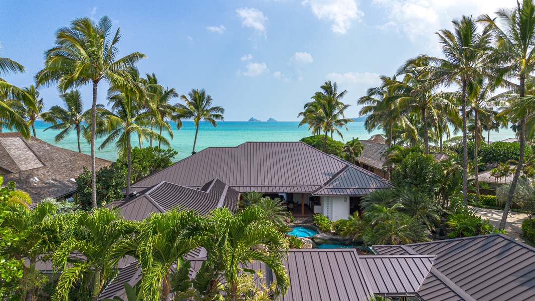 Roofline silhouette against tropical landscaping with glimpses of Kailua Bay beyond.