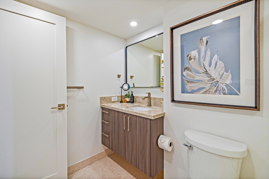 The bathroom features a stylish vanity with ample storage, framed wall art, and modern fixtures to create a clean and comfortable space.