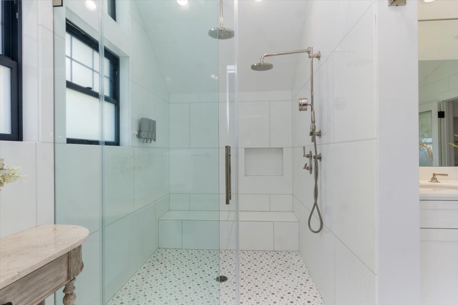 Glass-enclosed walk-in shower with dual rain heads and spa-style elegance.