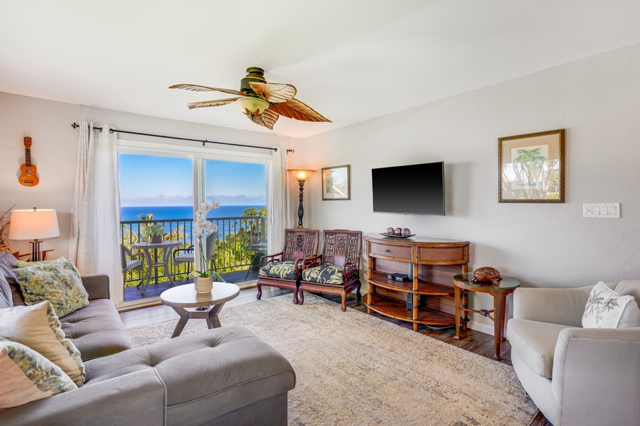 The living area, adorned with plush seating and a large ceiling fan seamlessly connects to the lanai.
