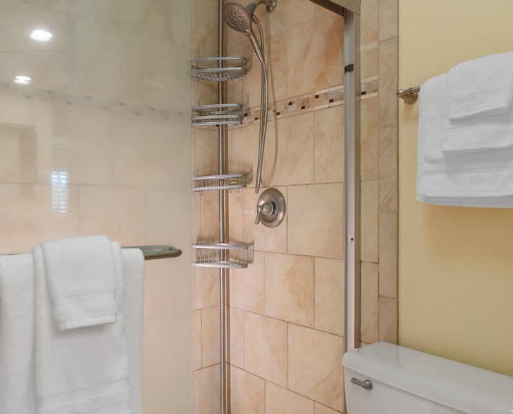 The third bathroom features a walk-in shower with sleek tile and fresh towels.