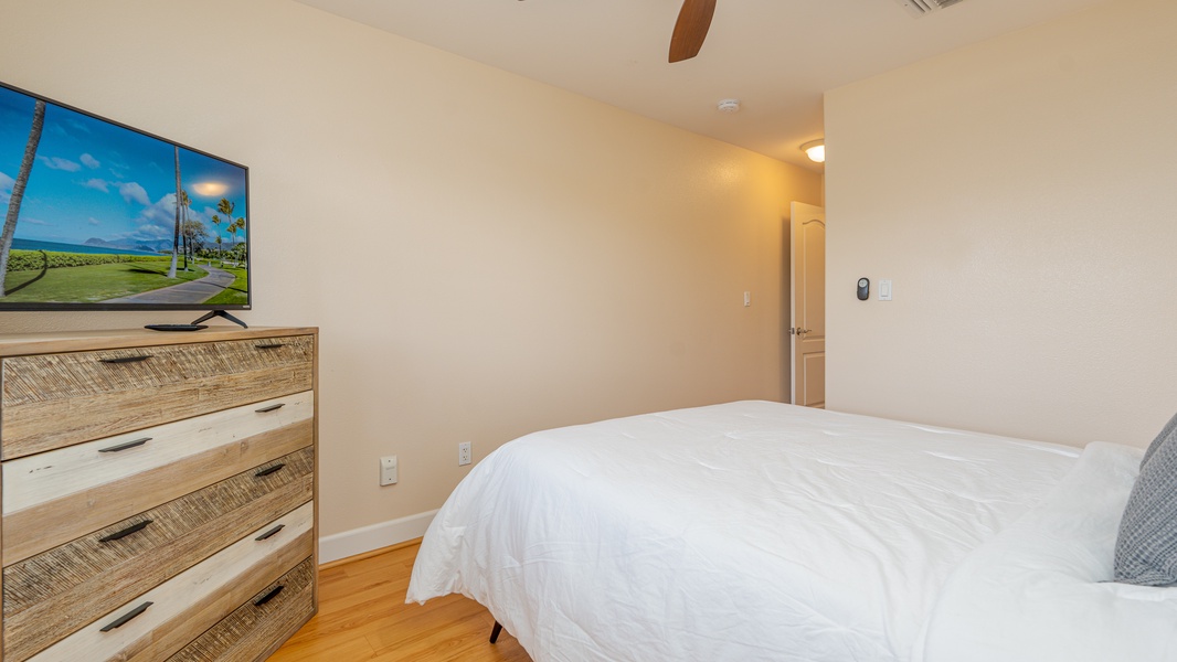 The second guest bedroom also features a dresser and ceiling fan.