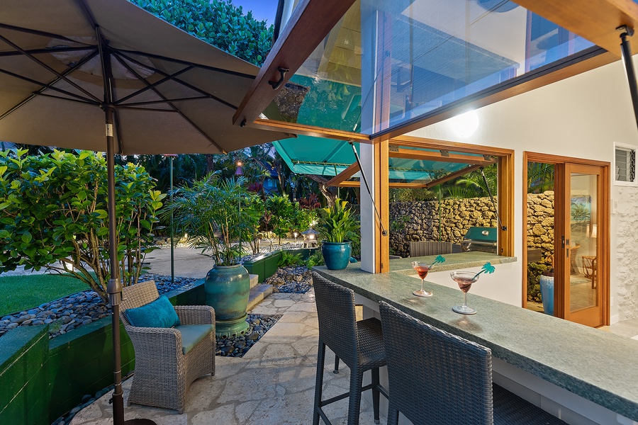 Open-air bar at the pool house surrounded by lush gardens, perfect for sipping cocktails and unwinding.