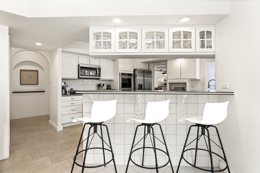 Sleek white cabinetry, stainless steel appliances, and a breakfast bar perfect for morning coffee.
