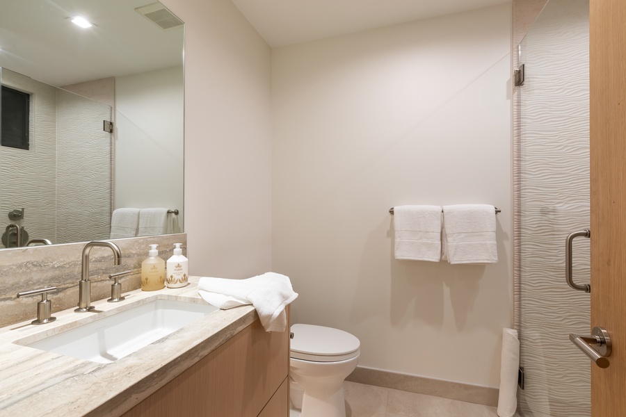 Step into your pristine bathroom featuring elegant marble countertops, plush towels, and a spacious shower with modern fixtures.