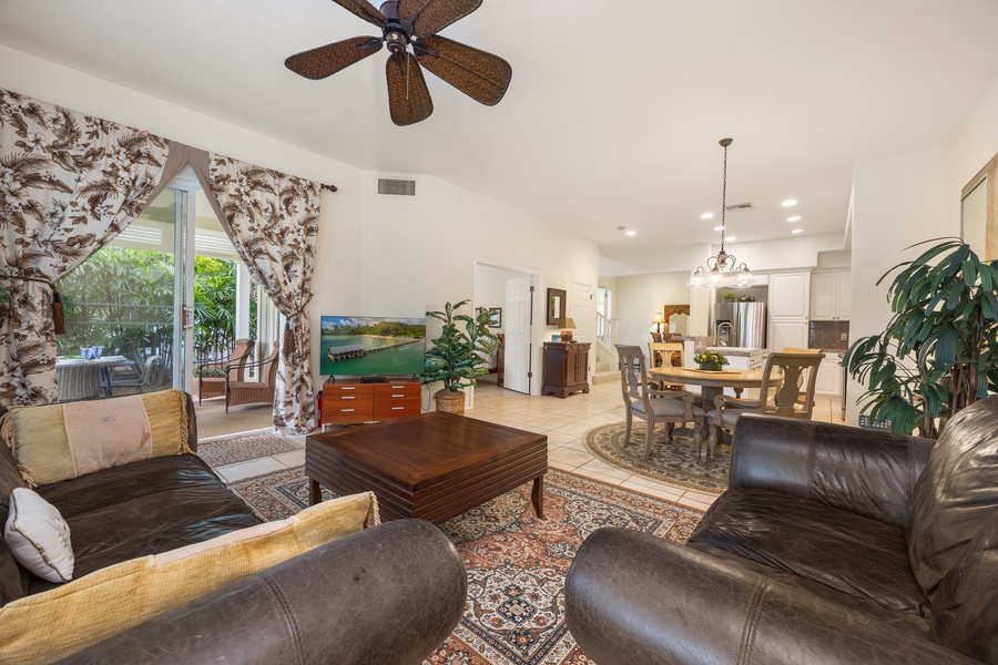 Settle into your spacious living room where rich leather seating and tropical plants create a warm, inviting atmosphere for relaxing evenings.