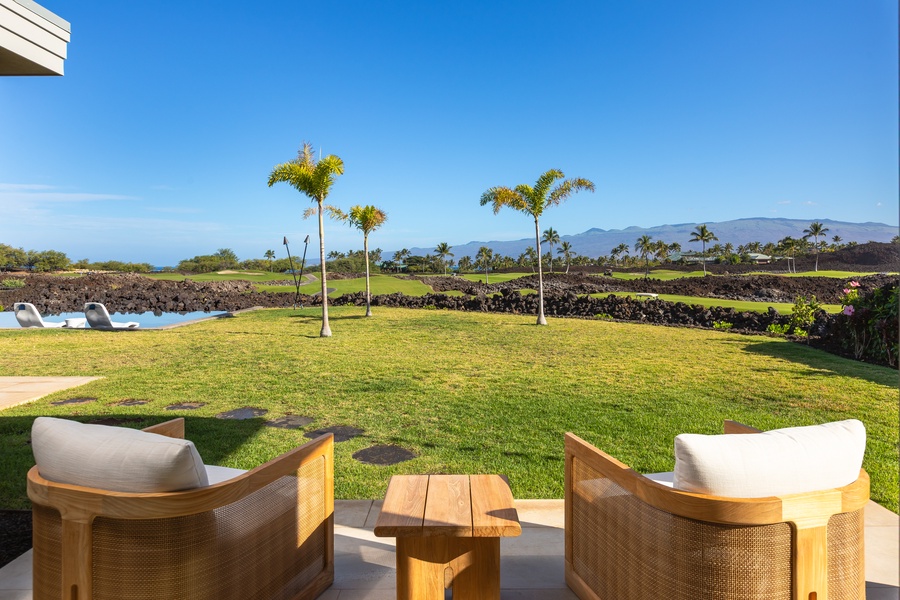 Your private lanai offers comfortable seating with stunning views of manicured lawns, swaying palms, and distant mountains under endless blue skies.