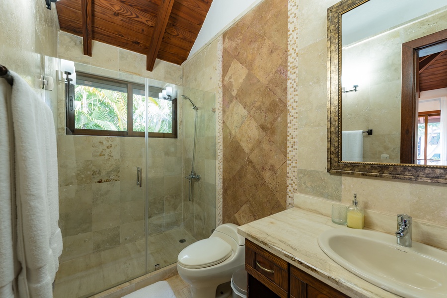 A full ensuite  bathroom with natural stone finishes and a large walk-in shower.