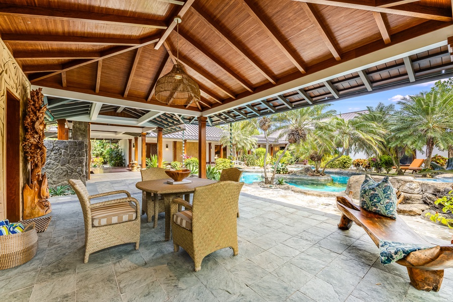 Resort-style poolside lanai offers outdoor dining with a backdrop of tropical gardens and water features.