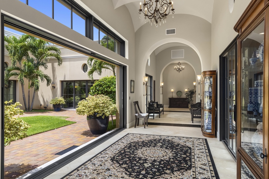 Bright hallway with high ceilings and arched windows, connecting indoor and outdoor living spaces seamlessly.