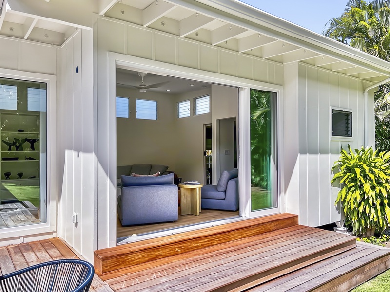 Sliding glass doors open to a covered deck and plush outdoor seating—blending comfort with coastal air and sunlight.