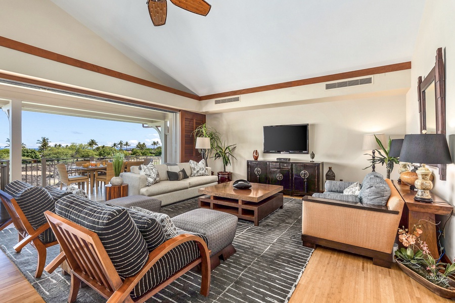 Living area with wall-mounted flat screen TV and sliding glass pocket doors to lanai