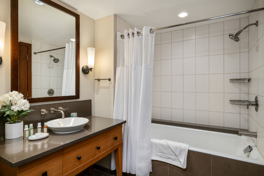 The guest bathroom features shower-tub combo with storage and large vanity.