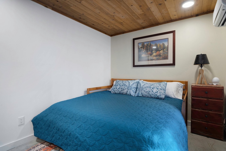 The second bedroom offers cozy comfort with a king bed, warm wood ceilings, and tranquil decor.