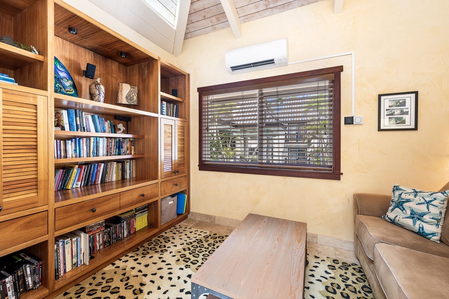 Custom library with a full book collection, cozy furnishings, and natural light—perfect for quiet reading or remote work.
