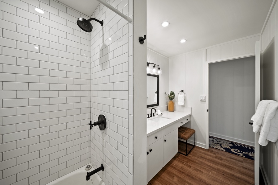 Walk-in shower with dark fixtures and timeless subway tile, blending contemporary design with beachside relaxation.