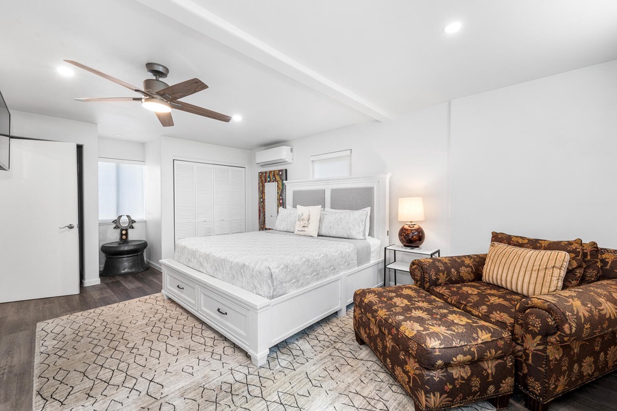 Spacious guest suite with queen bed, cozy seating, and calming neutral tones.