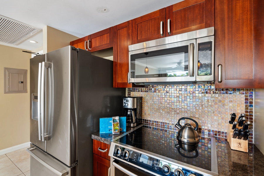 This kitchen in Honua Kai Konea 230/232 features a stylish backsplash and stainless steel appliances
