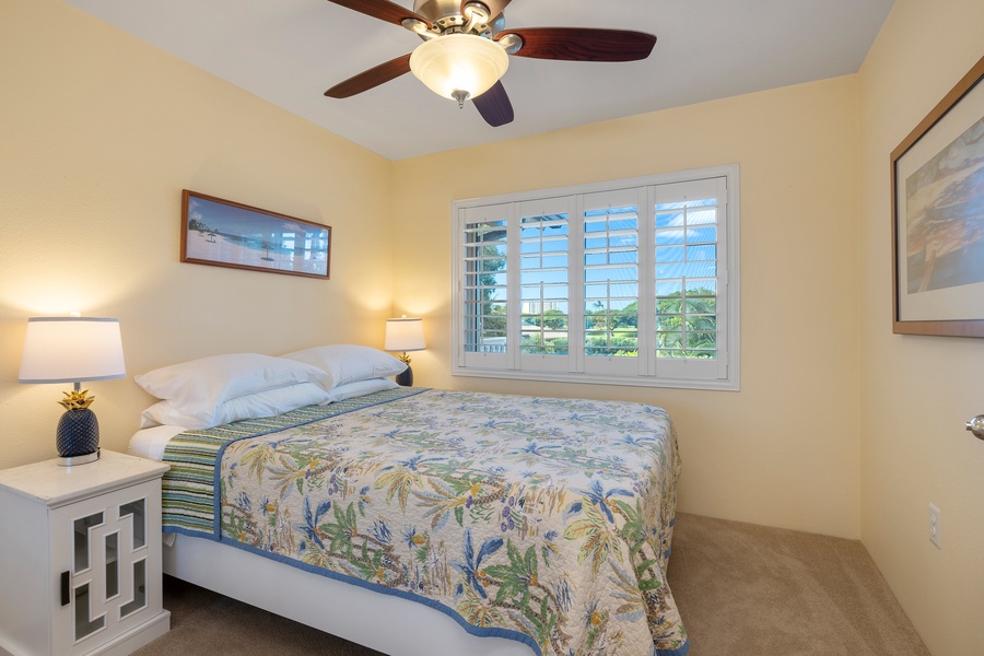 The second bedroom offers a cozy queen-size bed, natural light, and a ceiling fan for comfort.