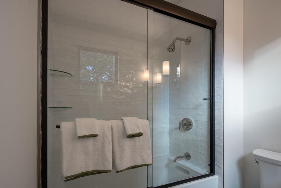 A shower/tub combo in a glass enclosure