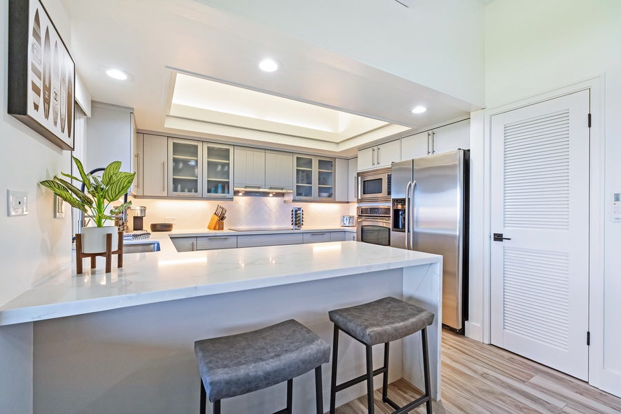 Kapalua Ridge 1421’s modern kitchen features sleek counters, stainless appliances, and bar seating.