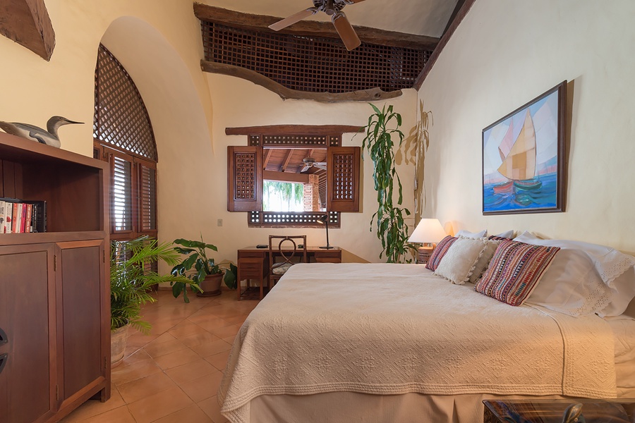 Airy guest bedroom featuring a comfortable bed and a cozy desk area with garden views.