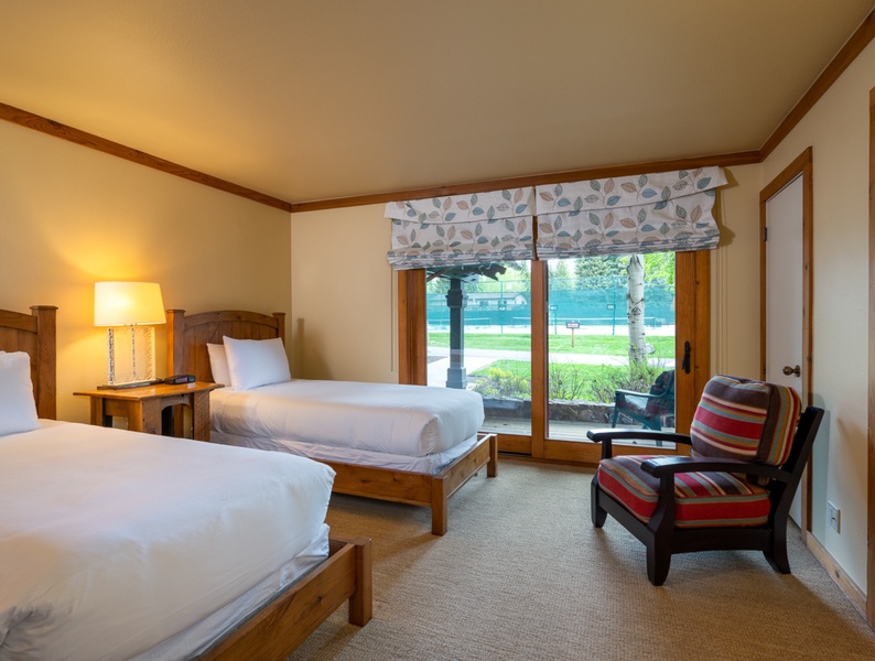 Indulge your guests in comfort and luxury with a spacious guest room featuring two inviting beds, and the added bonus of direct access to the deck