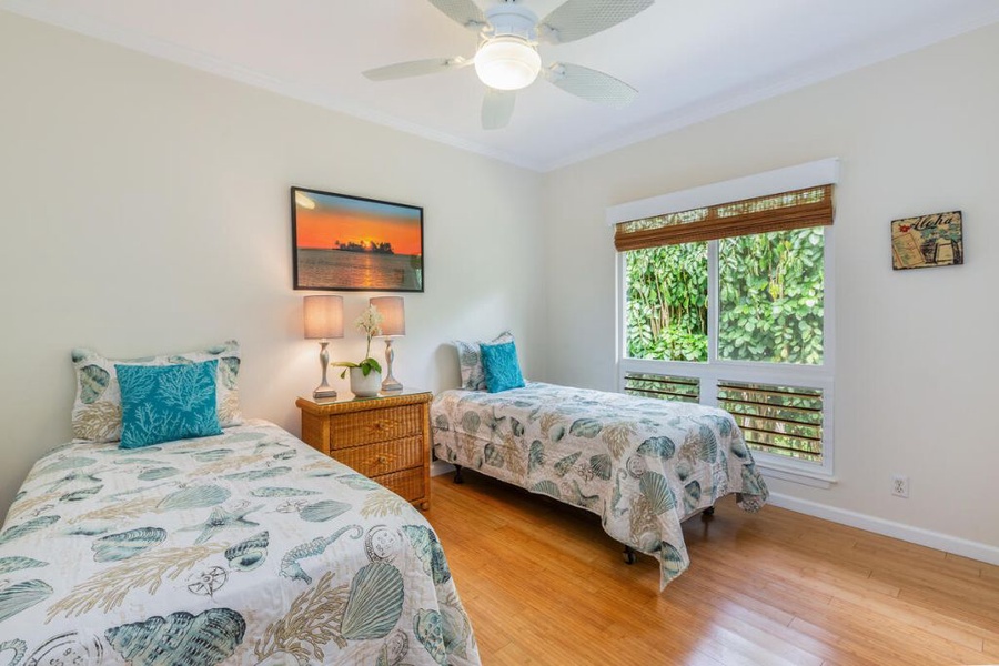The second guest bedroom has two twin beds and backyard views