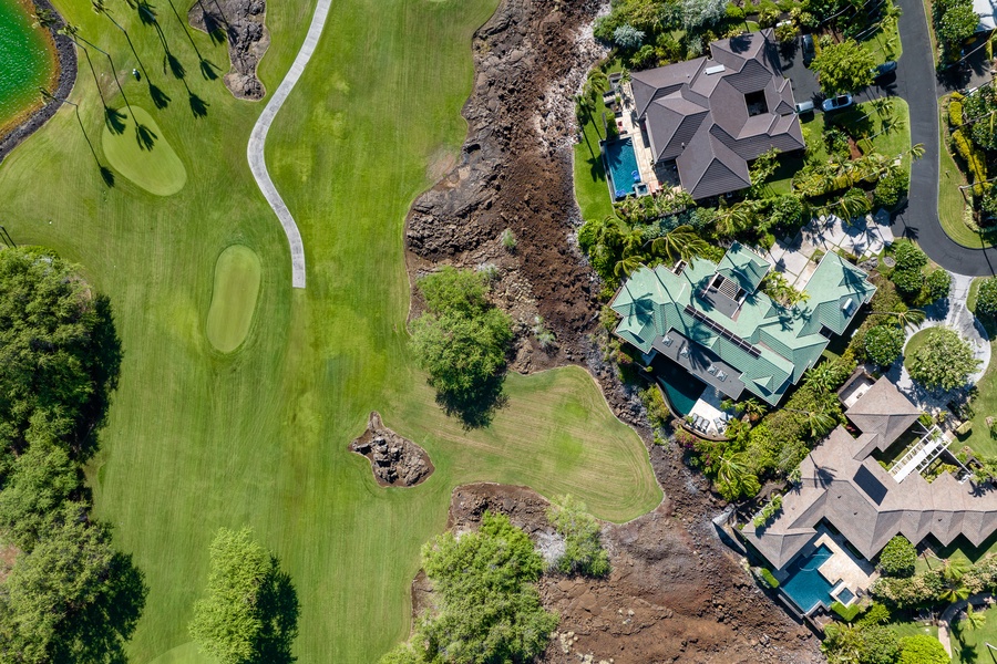 Aerial view of a home located next to a golf course, with pool and a serene and scenic setting for relaxation.