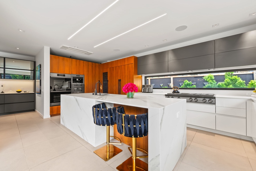 Enjoy the sleek modern kitchen with waterfall island, premium appliances, and warm wood accents.