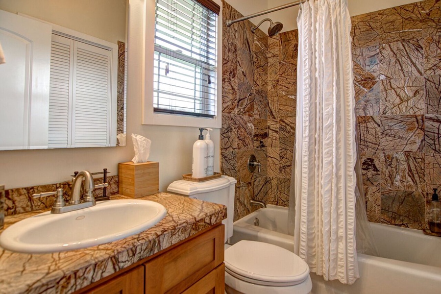The en-suite bathroom to bedroom 2 has a full tub with shower and elegant marble tile.