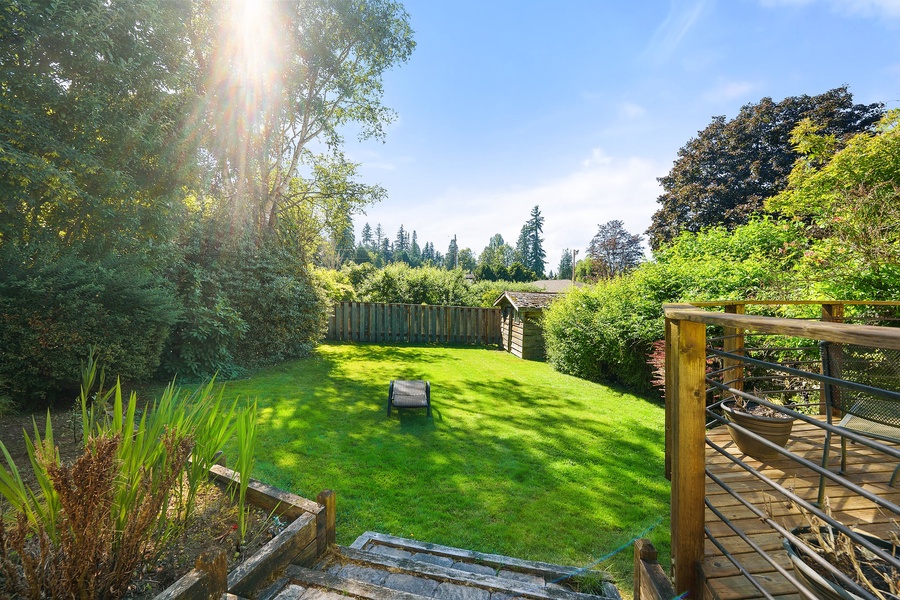 Spacious private garden with lush green lawn surrounded by mature trees, offering peaceful outdoor relaxation space.