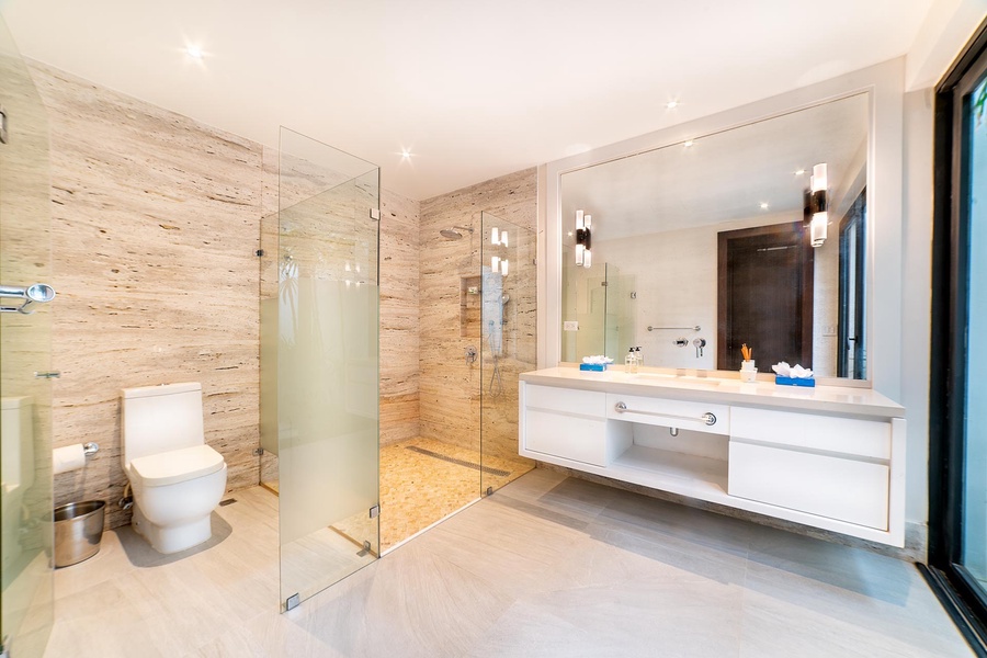 This ensuite bathroom features a large walk-in shower, dual vanities, and modern finishes.