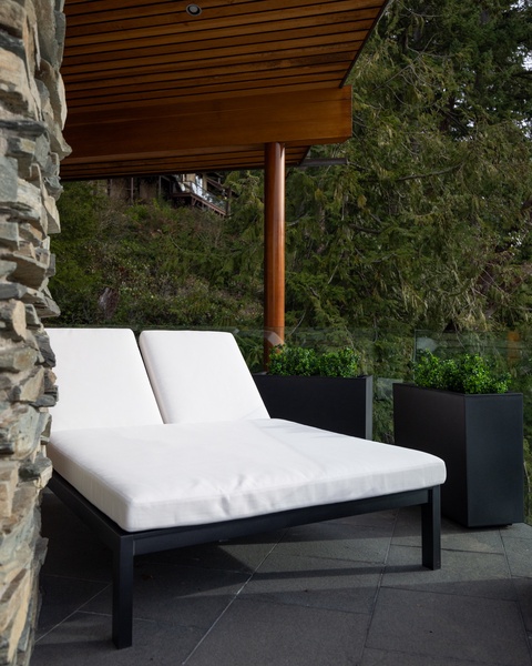 Unwind on luxurious outdoor loungers beneath your private covered terrace, surrounded by lush greenery and modern planters.