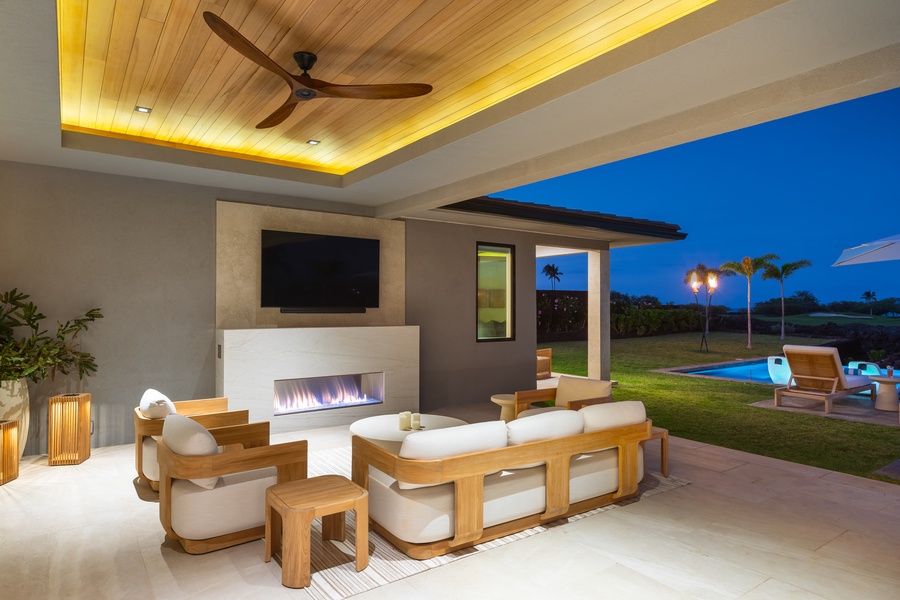 Elegant covered living space where modern comfort meets tropical luxury, complete with fireplace and pool views.