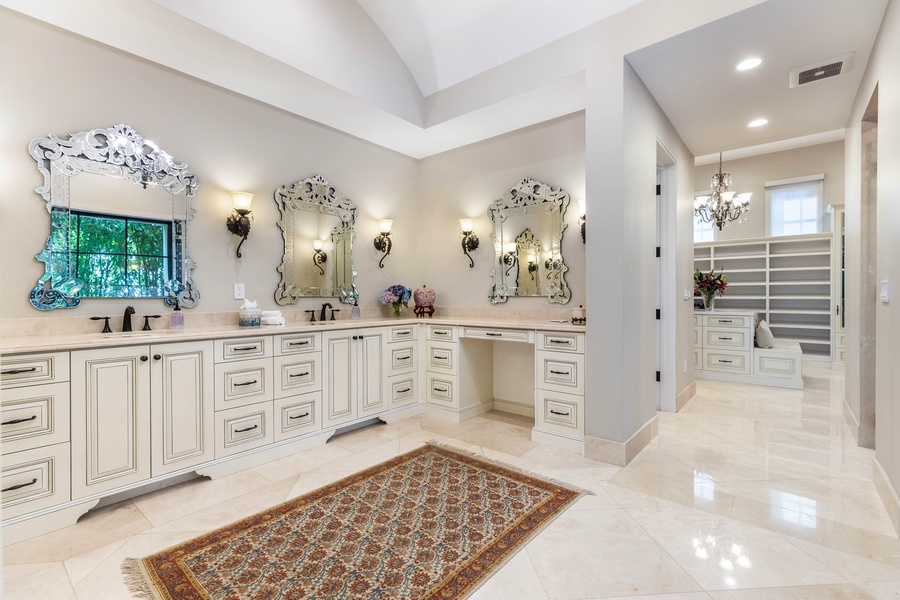 Stunning en-suite bathroom with dual vanities, intricate light fixtures, and a spacious layout.