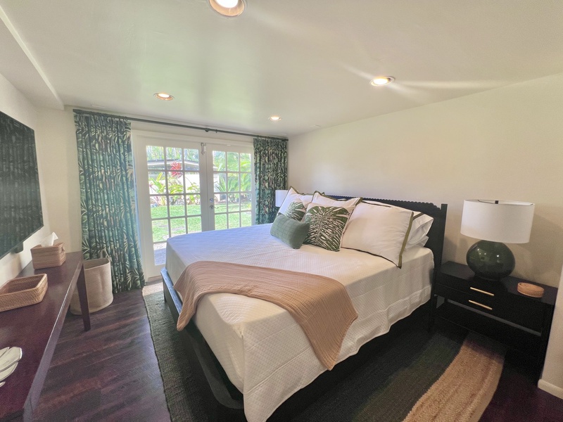 Guest bedroom featuring a queen-size bed, soft neutral tones, and private garden views