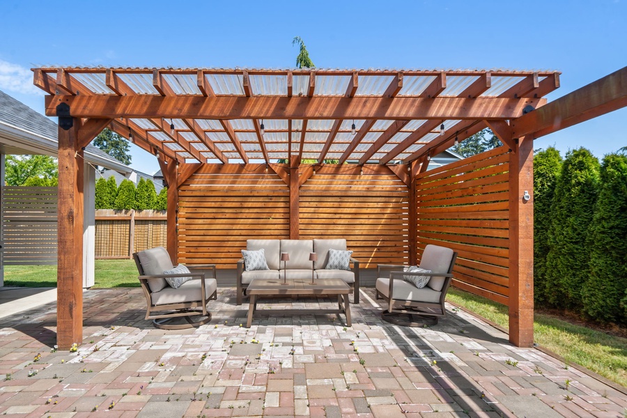 The spacious backyard offers green lawn space, mature privacy hedges, and a peaceful setting for outdoor relaxation.