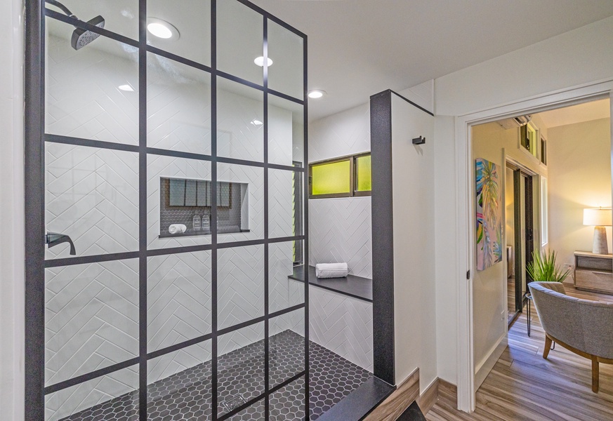 The spacious walk-in shower features modern black-framed glass panels, a convenient built-in bench, and stylish tile work that combines elegance and functionality