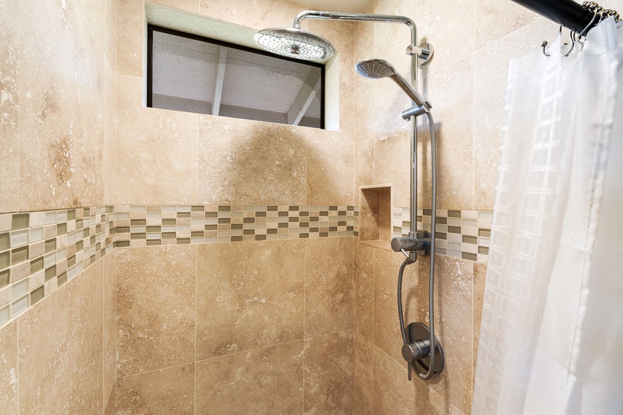 Step into your private sanctuary featuring a beautifully tiled shower with dual rainfall and handheld fixtures, plus a built-in niche for your essentials.