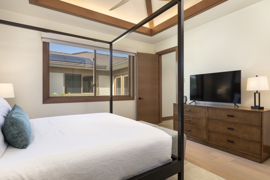 Reverse view of the guest suite three with a storage, TV and bright windows.