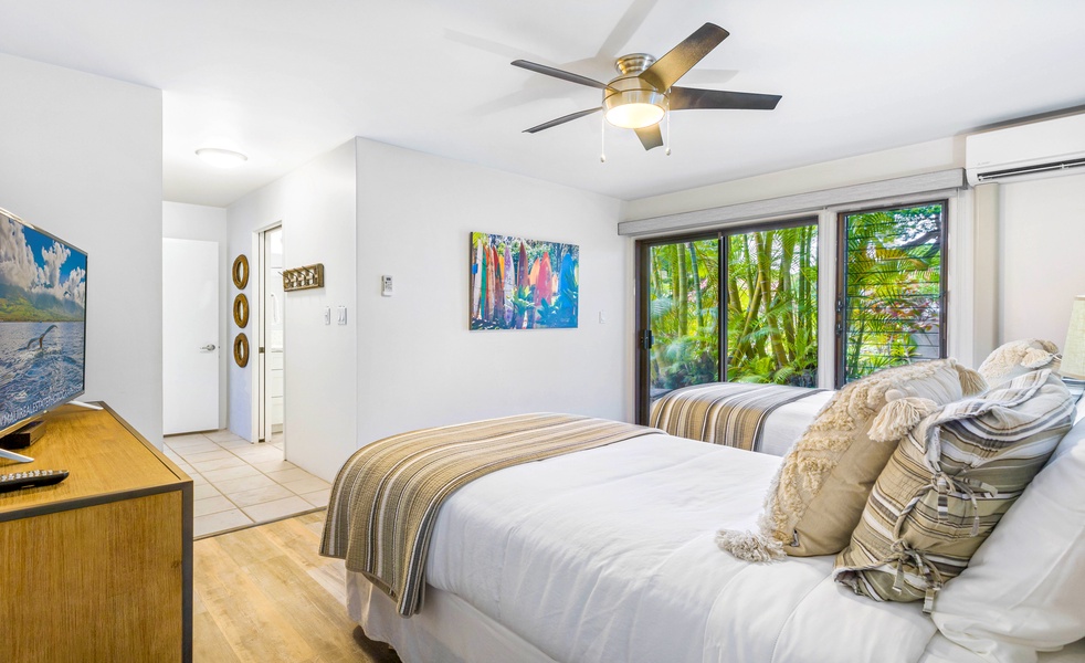 A bright bedroom with twin beds and views of lush greenery just outside the window, creating a peaceful atmosphere for rest.