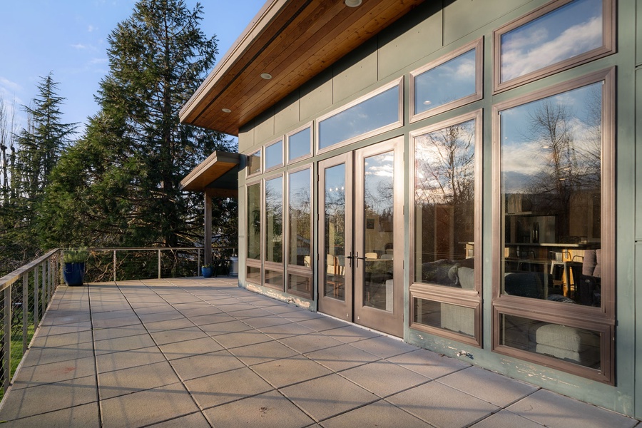 Step onto your private lanai with floor-to-ceiling windows framing forest views. Natural light floods the modern space while you relax outdoors.