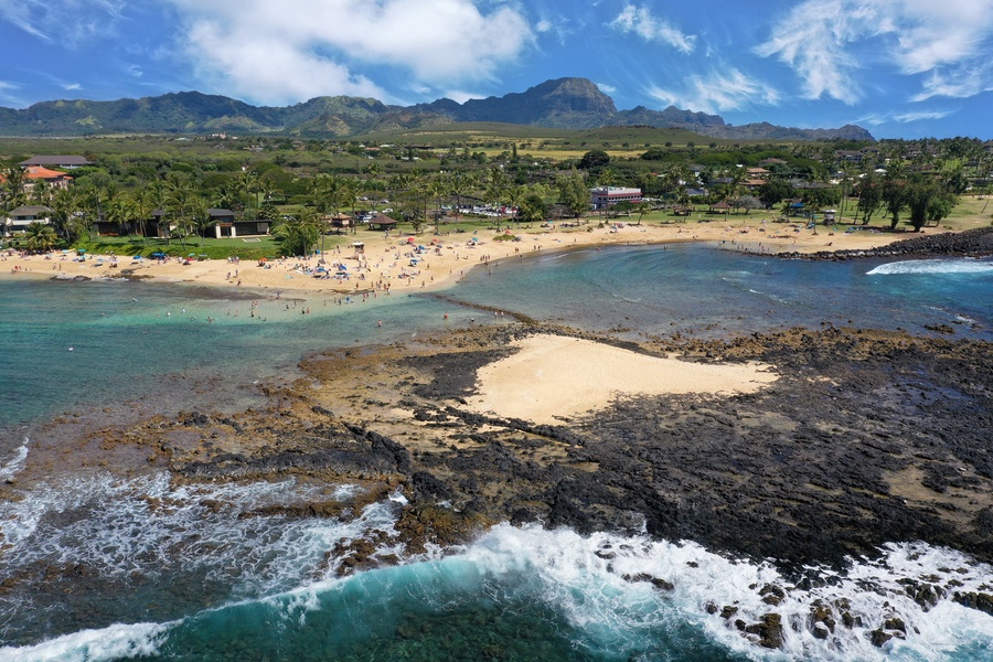 Curved golden beach framed by lava rock and calm blue surf.