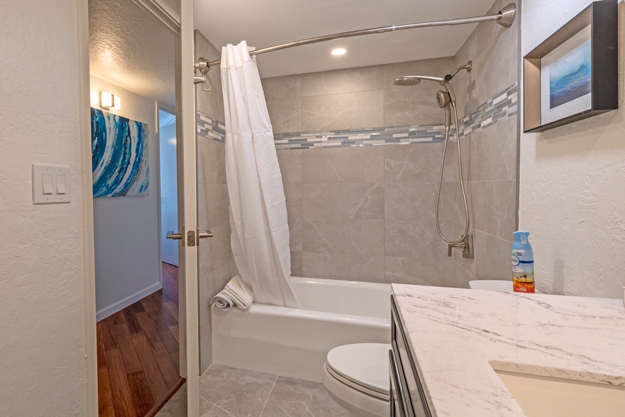 The bathroom features a modern tub and shower combination with stylish tile accents