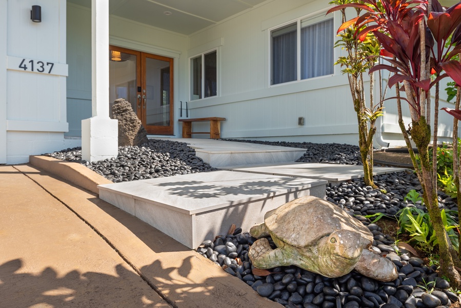 Welcoming front entrance with a landscaped pathway and tropical plants.