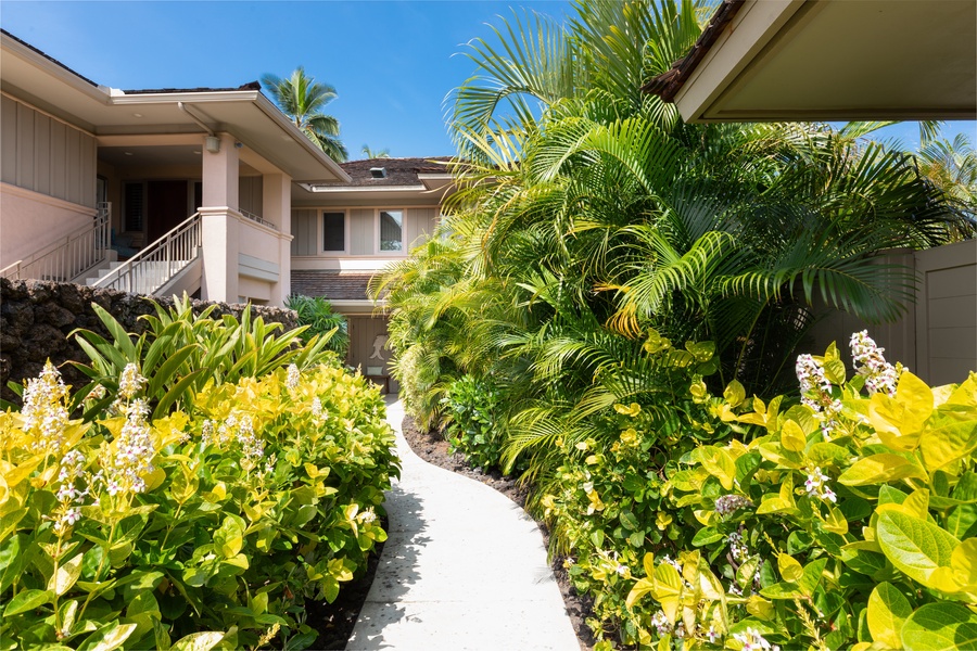 A tropical paradise pathway lined with vibrant palms and flowering plants leads to your villa.