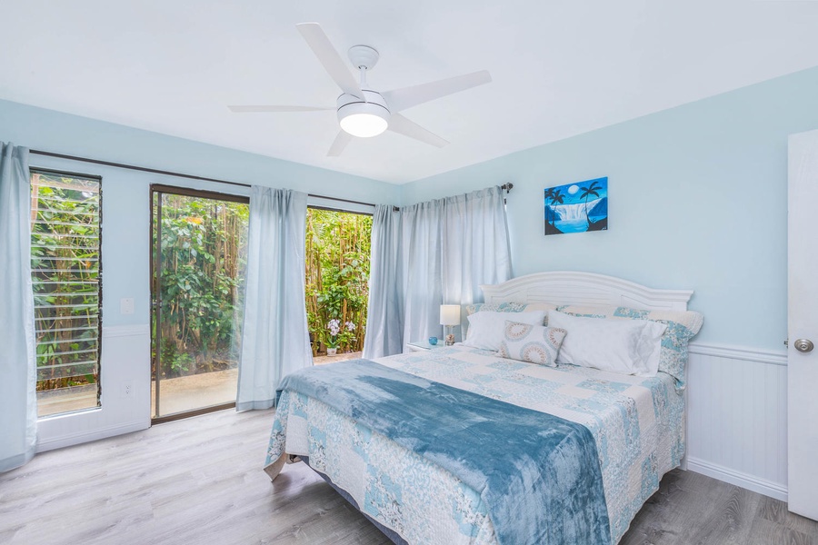 A tranquil guest bedroom featuring soft blue tones, a plush bed, and private access to the outdoor garden area.