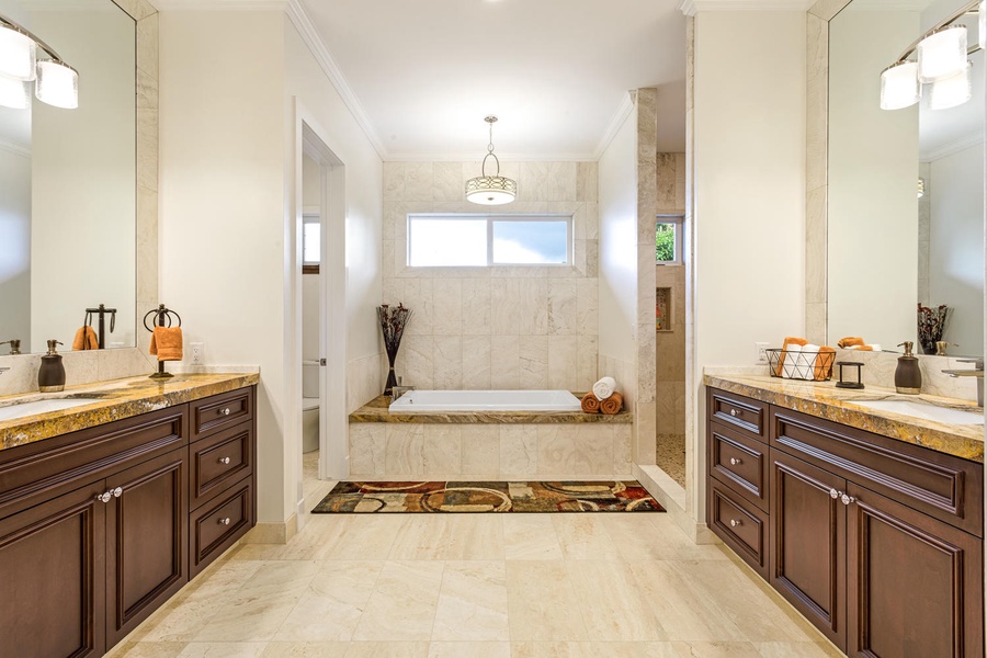 en suite bath with a soaking tub, two walk-in showers, a vanity, and dual walk-in closets.