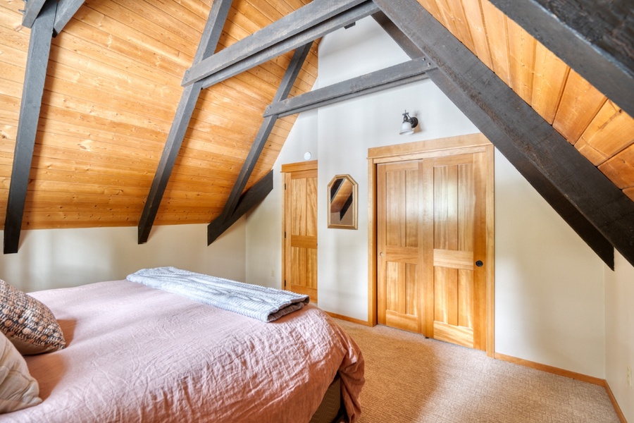 The guest bedroom features a built-in closet and vaulted ceiling for a rustic feel